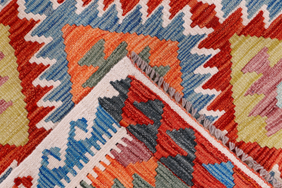 Kilim rug corner close-up with red, blue, orange, and cream diamond pattern