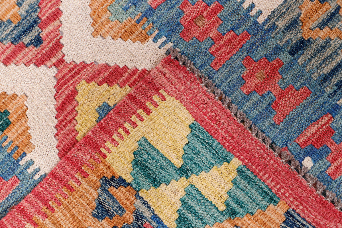 Diagonal close-up of multicolor kilim rug with diamond centerpiece and red edging