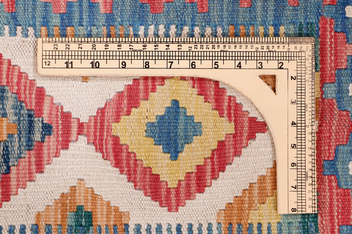Blue, red, and cream kilim rug detail with diamond motifs and measuring ruler