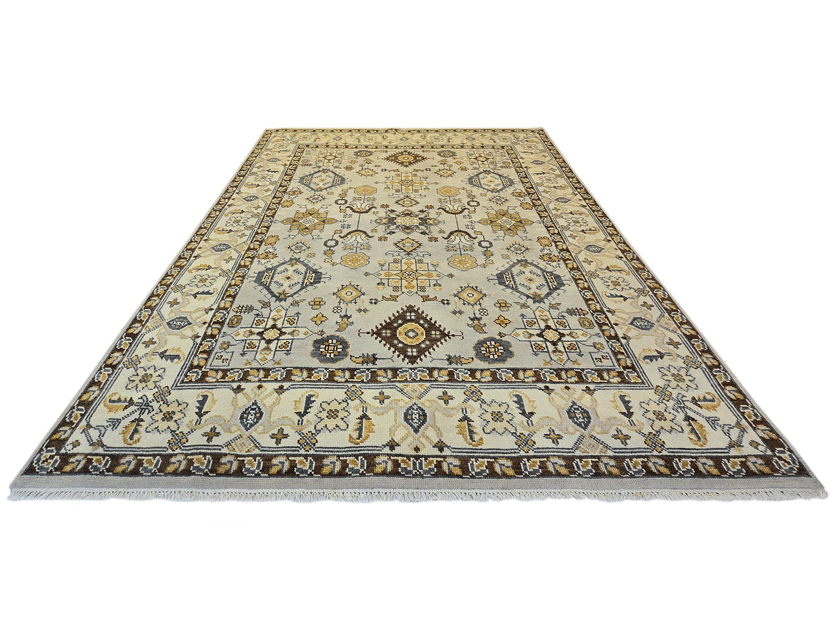 Oushak rug with beige center panel, navy and gold geometric motifs, fringed edges.