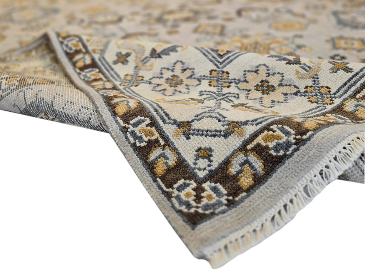 Oushak rug corner detail with ivory floral diamonds and navy trim, tasseled fringe edge.
