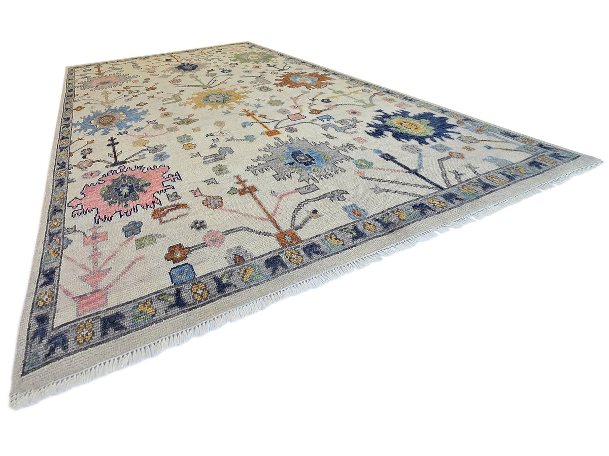 Oushak rug with light beige ground, blue and navy edging, and multicolor floral and cross motifs