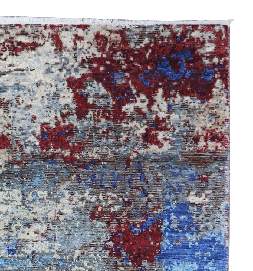 Close-up of abstract area rug with blue and crimson distressed blocks on white
