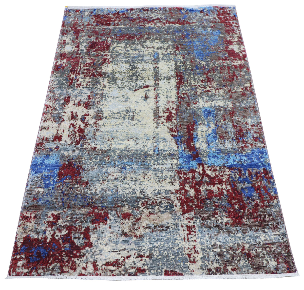 Flatweave abstract rug with cream base and scattered blue and crimson distress marks