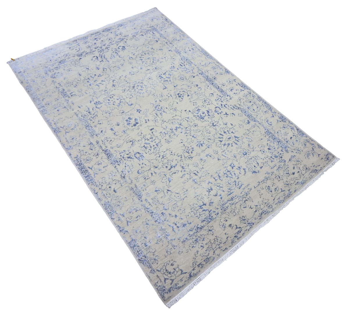 Ice blue rug laid diagonally with distressed floral pattern and flat, textured weave