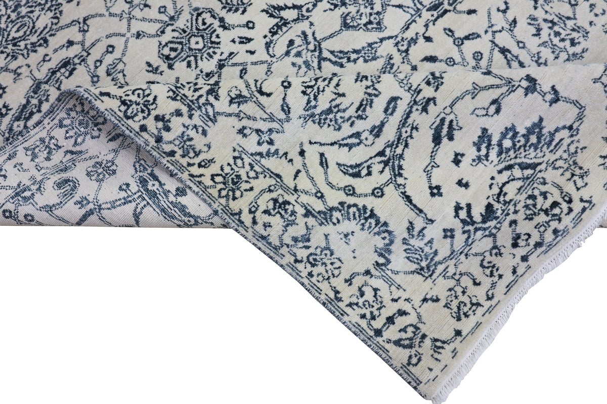 Off-white rug corner with blue ornamental vines and border stripe detail