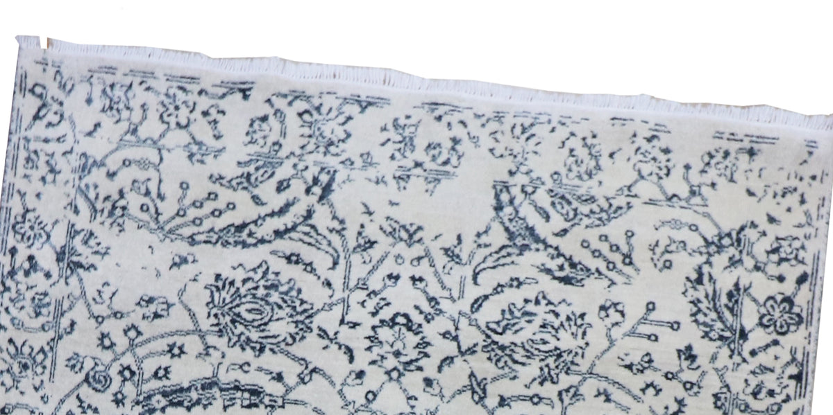 Off-white rug edge with blue floral motifs and fringe trim