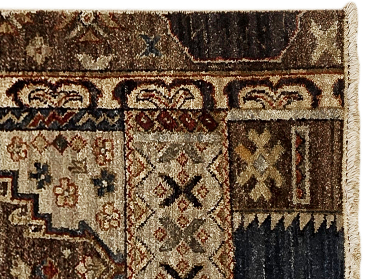 Close-up of patchwork rug showing bordered motifs in brown, cream, navy, and red