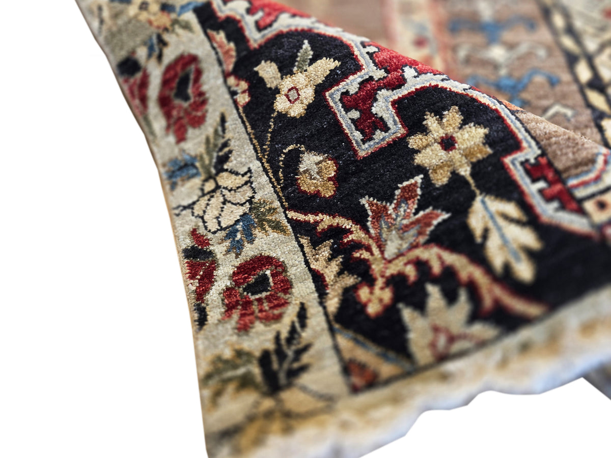 Patchwork rug corner detail with dark navy, red, and cream patterns and short fringe