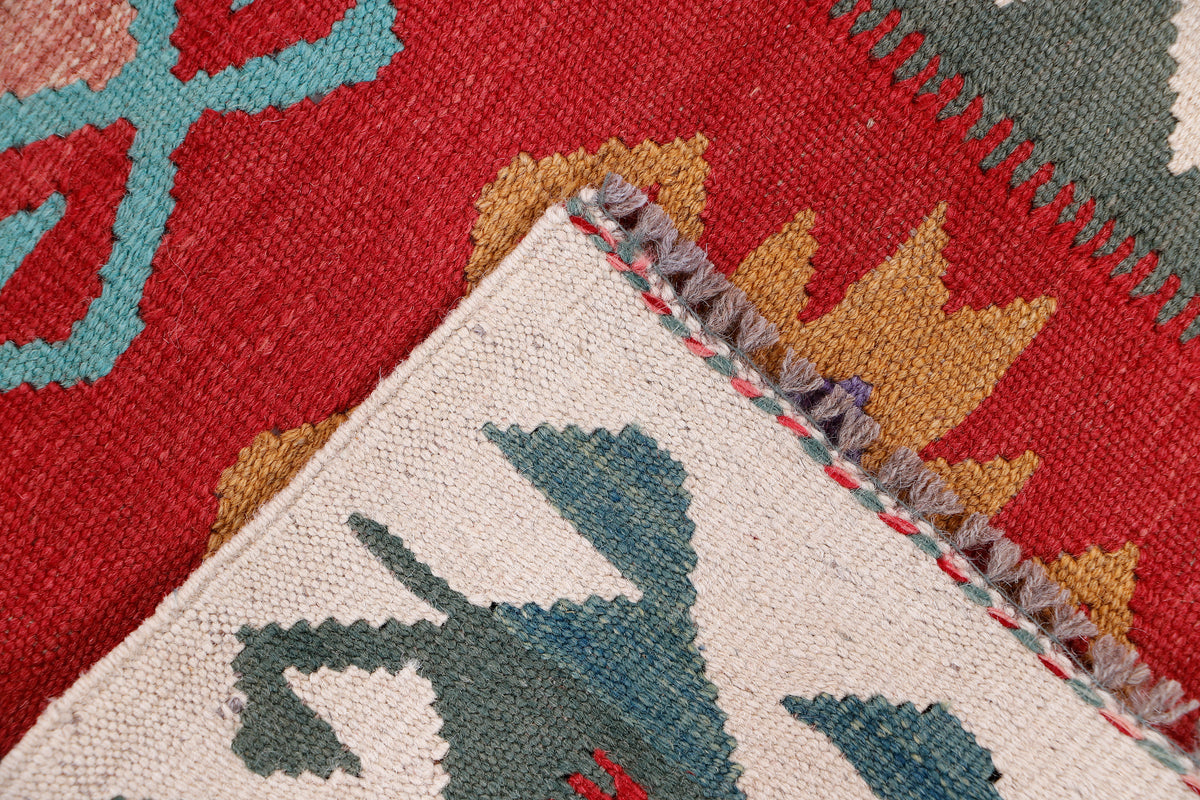 Kilim rug corner with woven motifs in red, blue and beige and short fringed edge