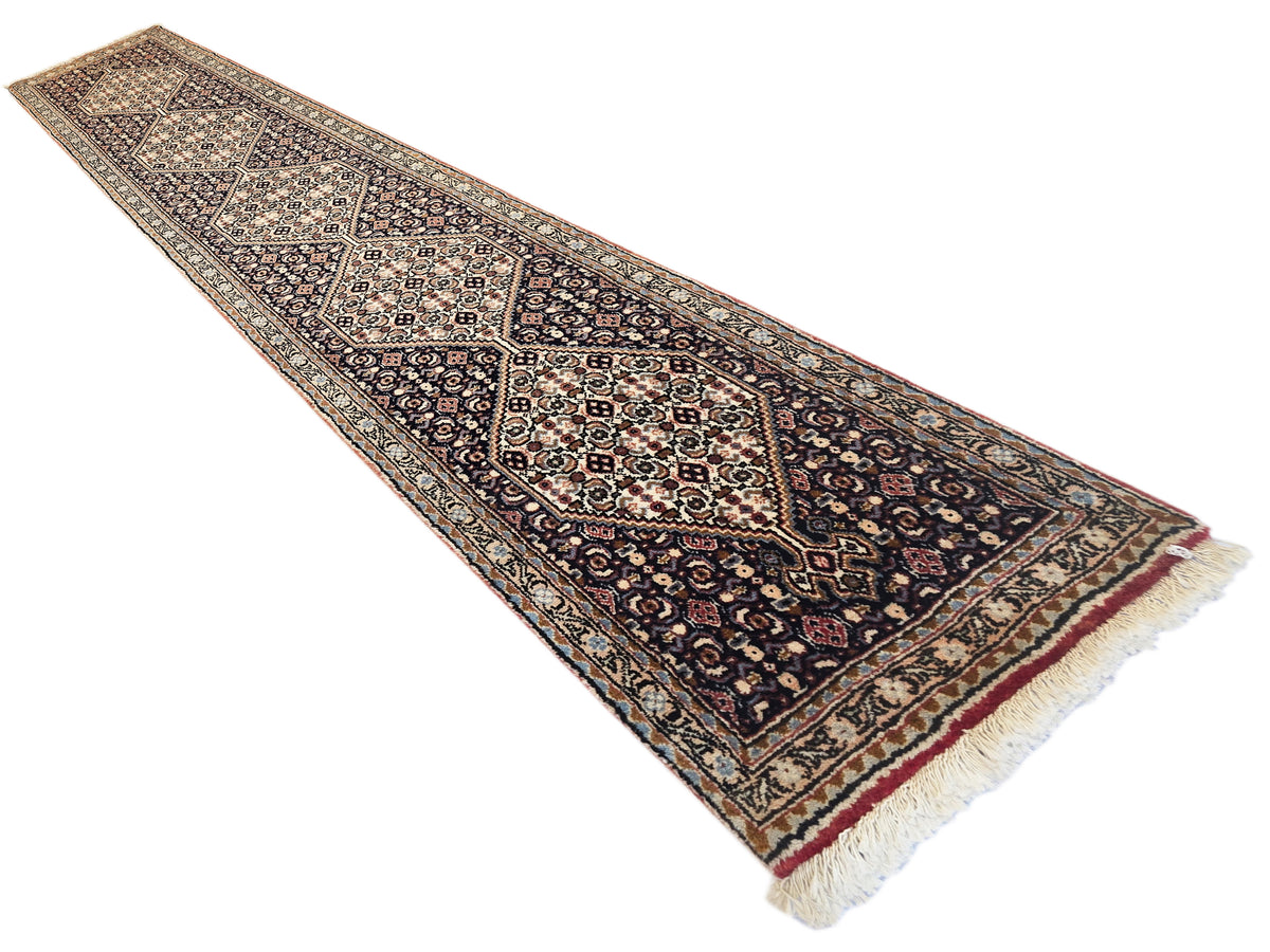 Dark patterned runner rug with geometric medallion, tan border, and short cream fringe