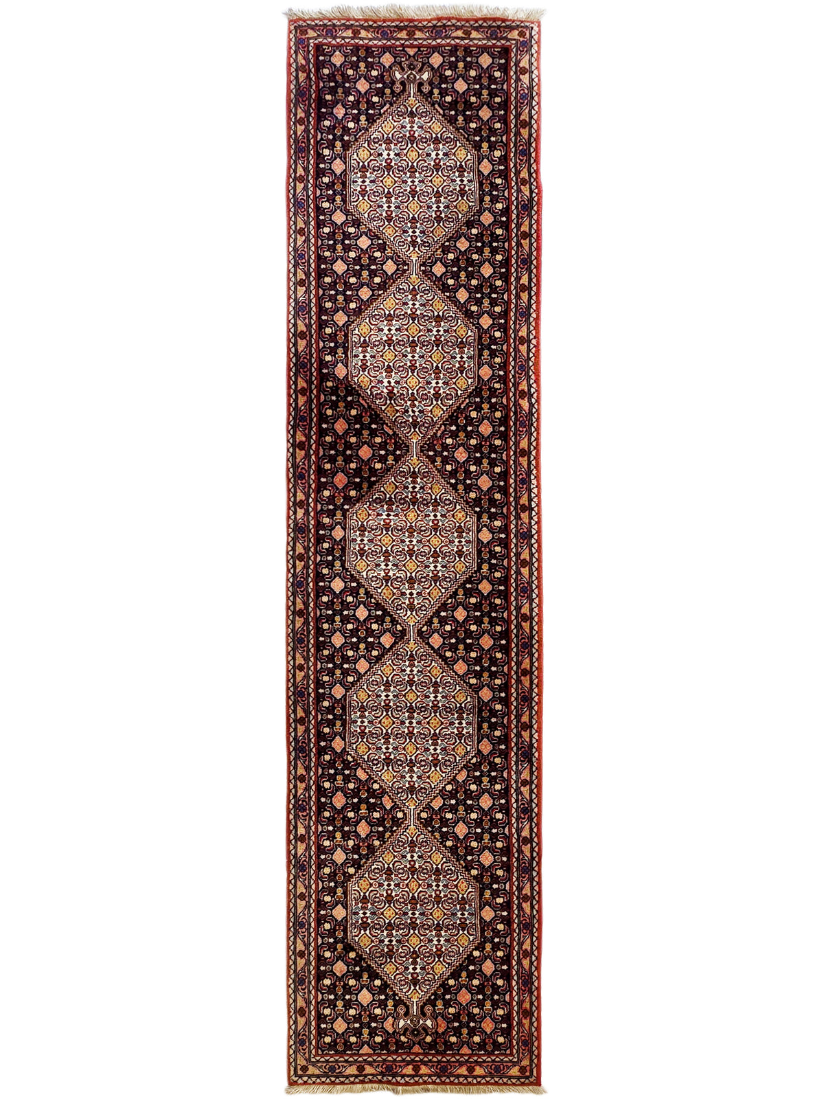 Straight view of narrow runner rug with dark background, red border, and repeating diamond medallions.