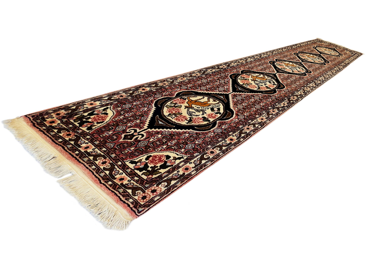 Narrow runner rug with maroon and beige ornate medallion pattern and fringe ends