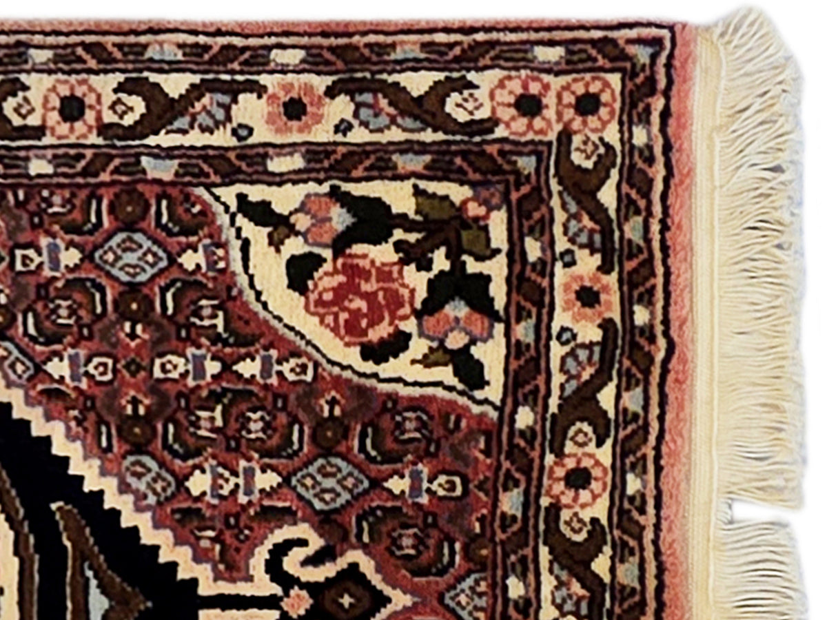 Close-up of runner rug with detailed maroon and cream border motifs and fringe