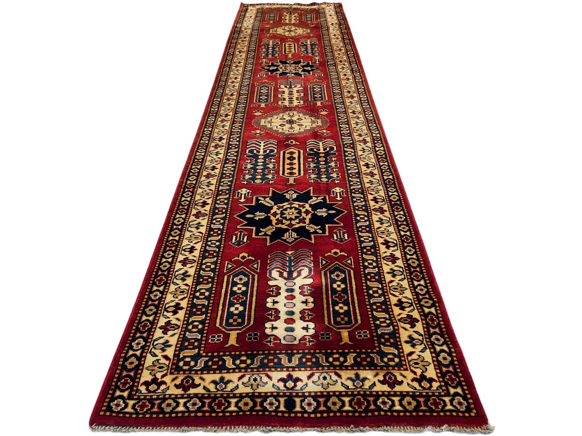Narrow rectangular Sherwan rug with red central medallion and cream with navy motifs.