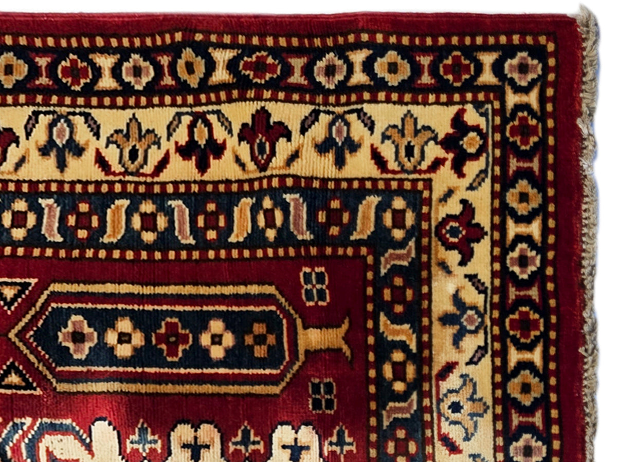 Close-up of Sherwan rug border in maroon and cream with repeating geometric bands.