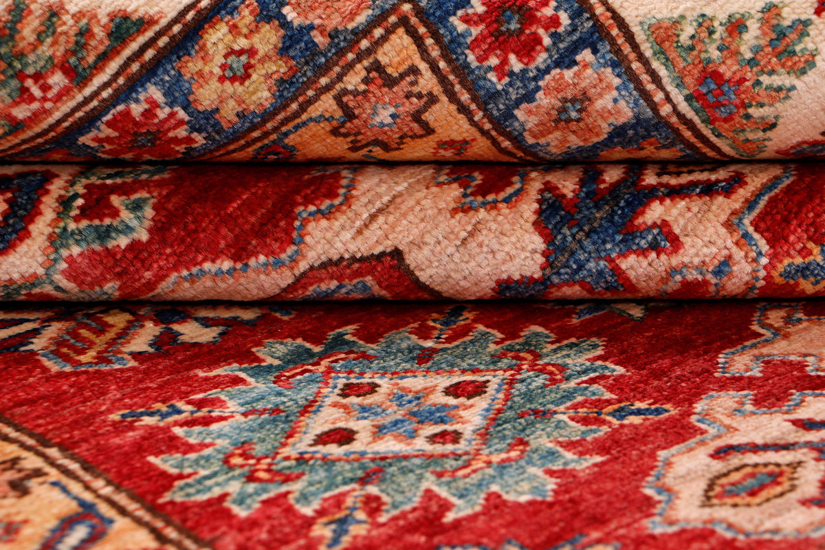 Red Kazak rug corner close-up with folded pile and multicolor motifs, 198x155 cm