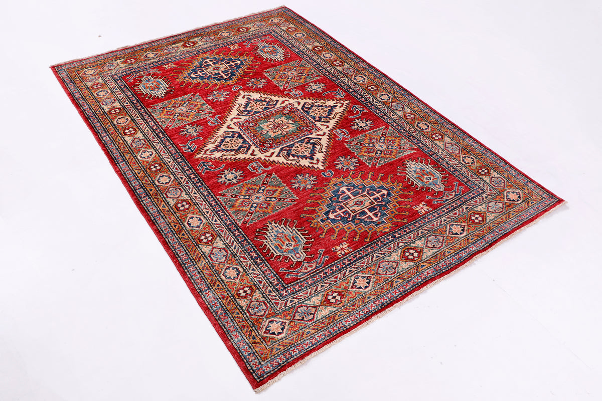Red Kazak area rug with central medallion and ornate border in blue and cream