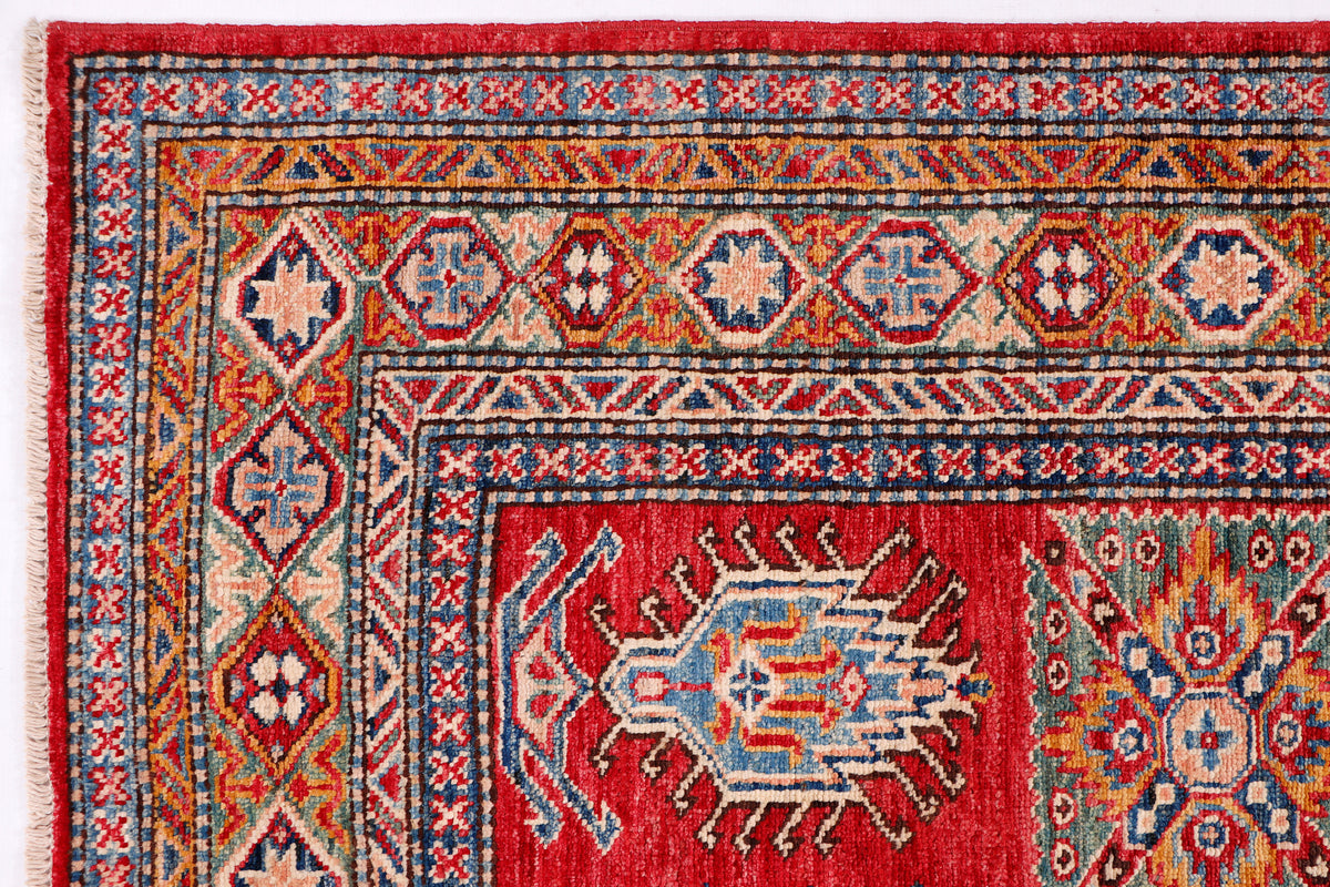 Red patterned Kazak rug with blue and cream geometric border detail