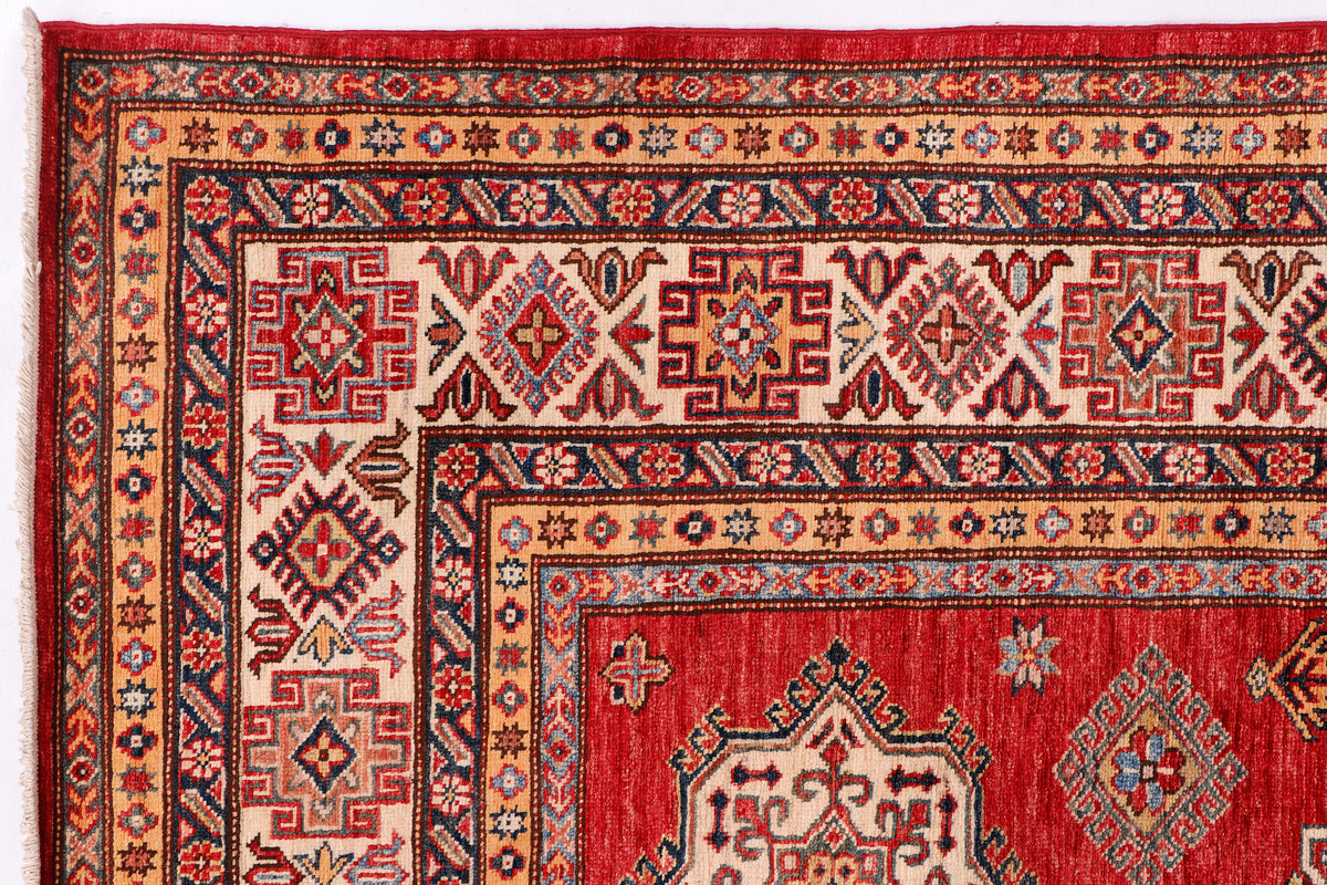Close-up of red rug border with repeating geometric stars and frame motifs.