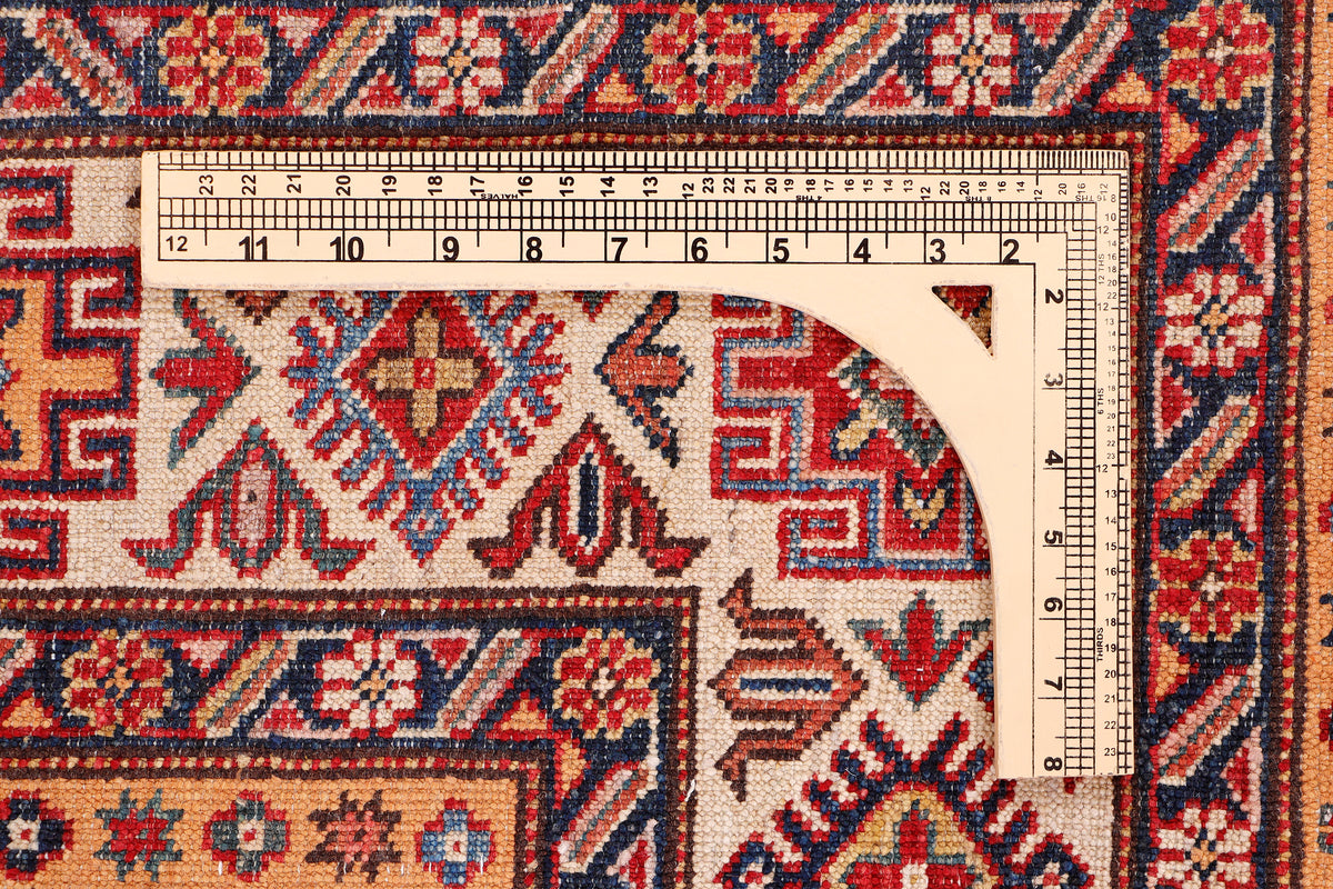 Red rug corner with intricate motifs; includes measuring tape along edge.