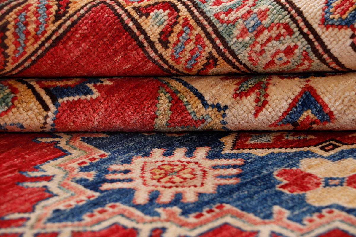 Red and cream rug close-up with blue geometric motifs and folded edge