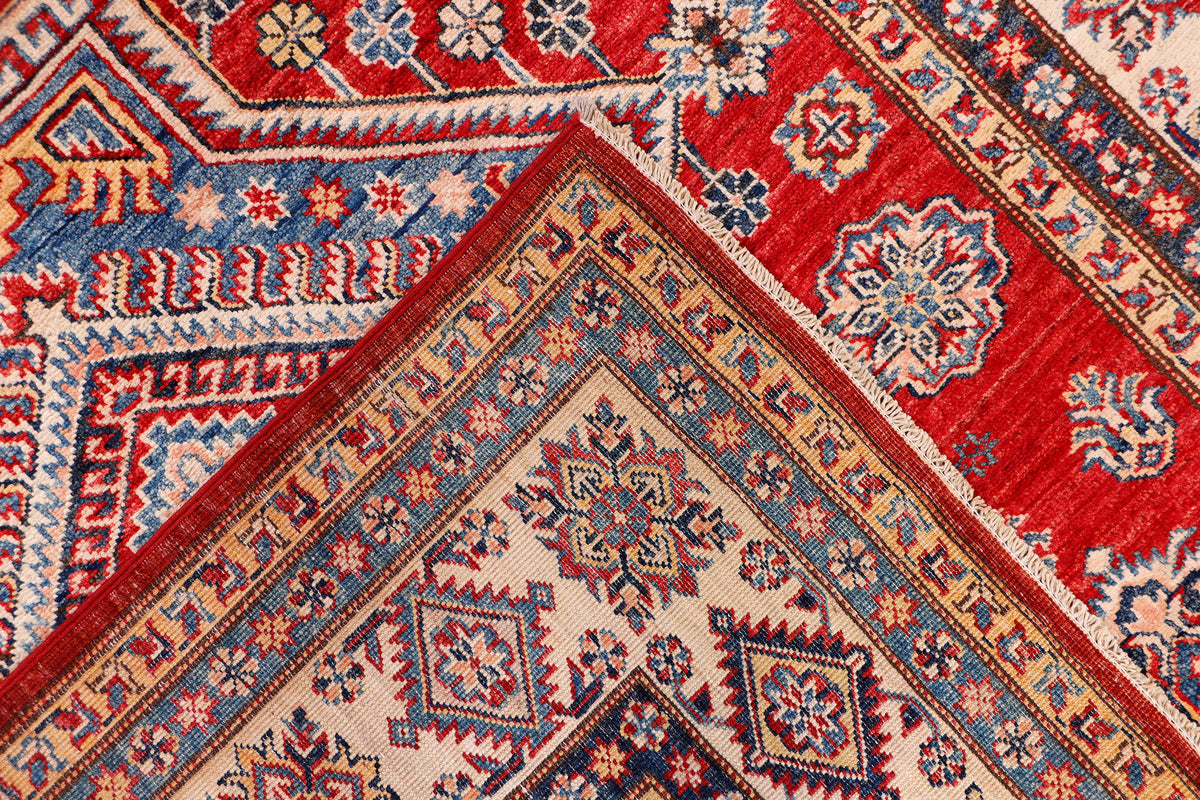 Kazak rug corner detail with red background, diamond motifs, and blue accents