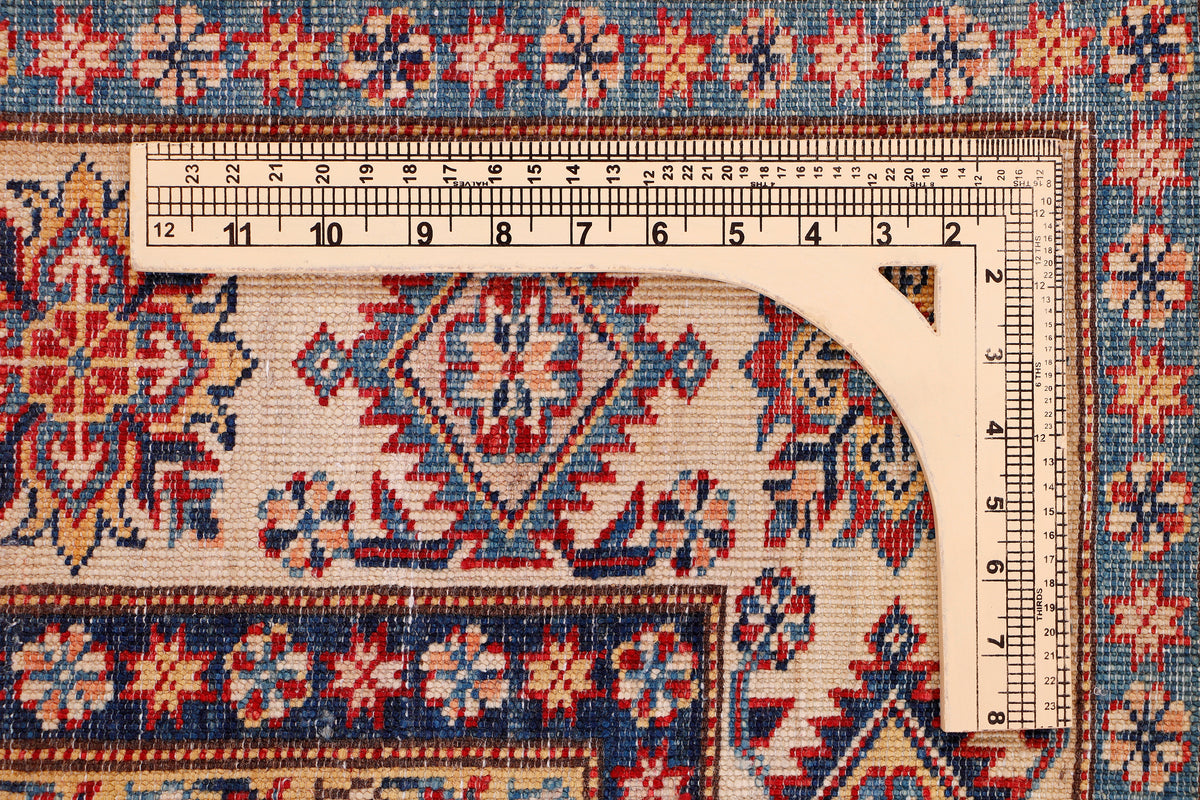 Kazak rug corner with measuring tape, red field with blue and ivory pattern