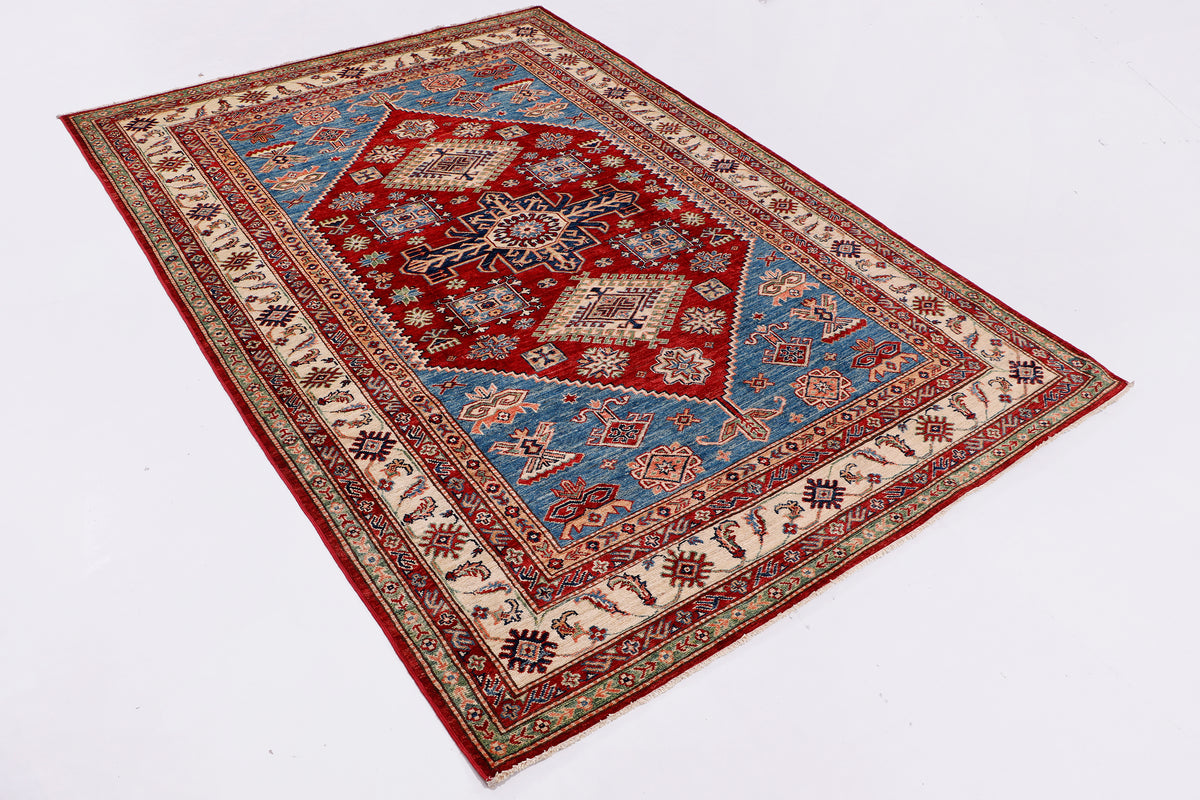 Red Kazak rug laid flat, featuring diamond motifs and ornate geometric border