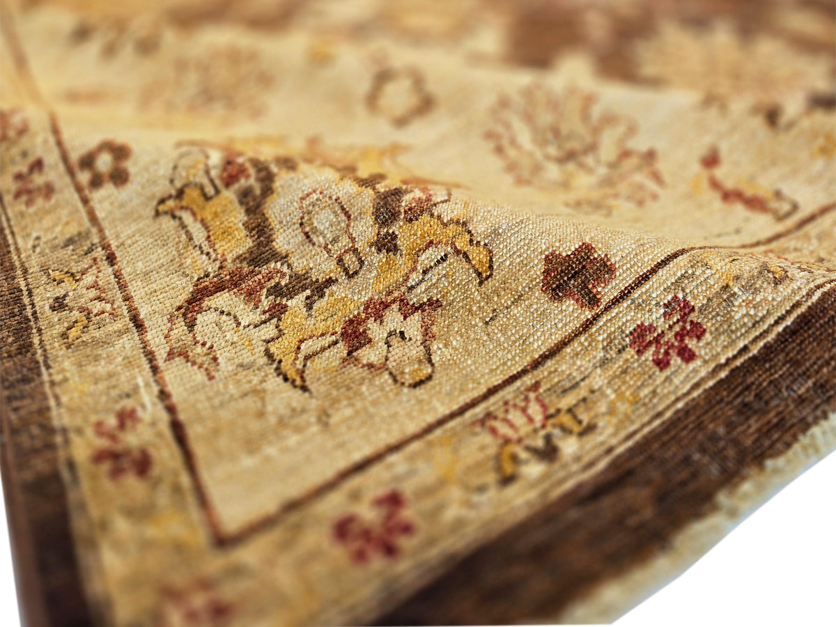 Close-up of rug corner showing tan base, dark floral design, and fringed edge
