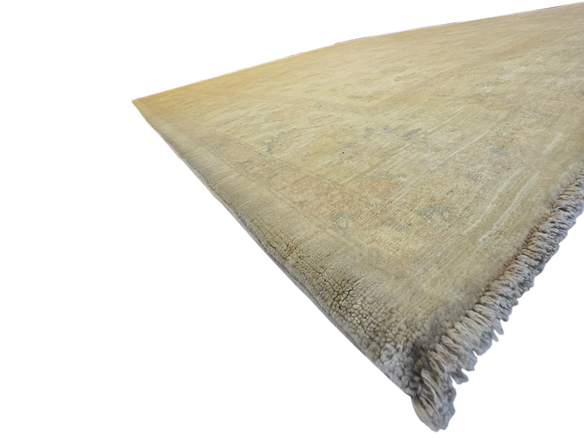 Beige rectangular rug with short gray fringe on one corner, faded abstract pattern