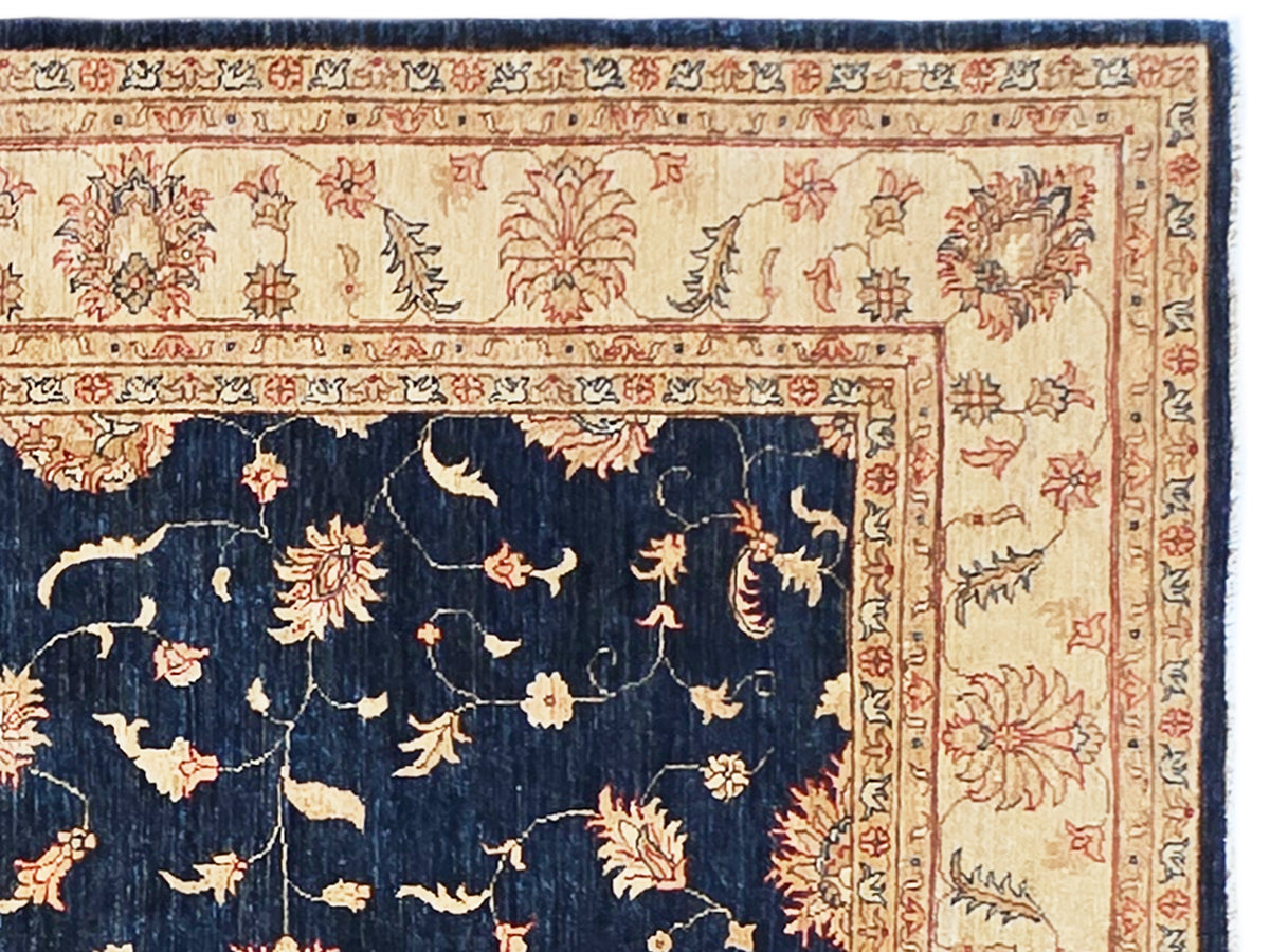 Close-up of navy rug with cream field, ornate red floral border and decorative motifs.