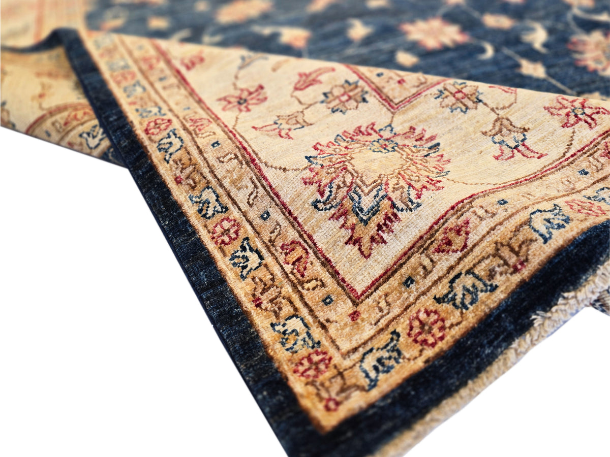 Navy rug corner detail with cream center medallion, red accents, and short fringe trim.