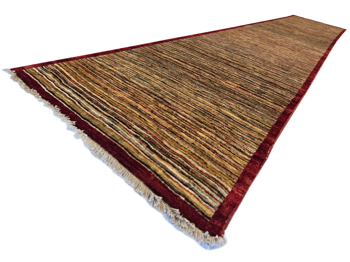 Gabbeh runner rug at angle, brown and multicolor stripe lines with red edge.