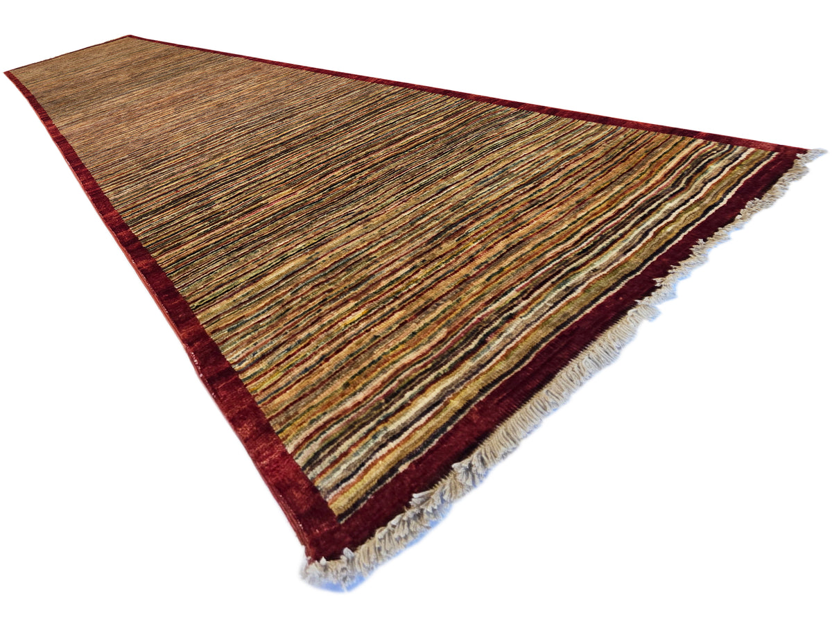 Gabbeh runner rug corner view, brown striped weave with dark red border and fringe.