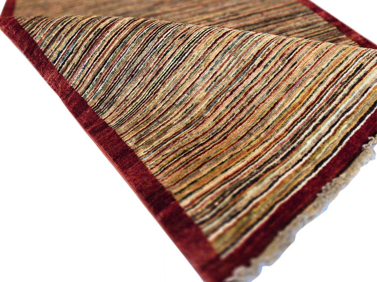 Gabbeh runner rug angled view, beige and brown stripes with dark red border and tassel ends.