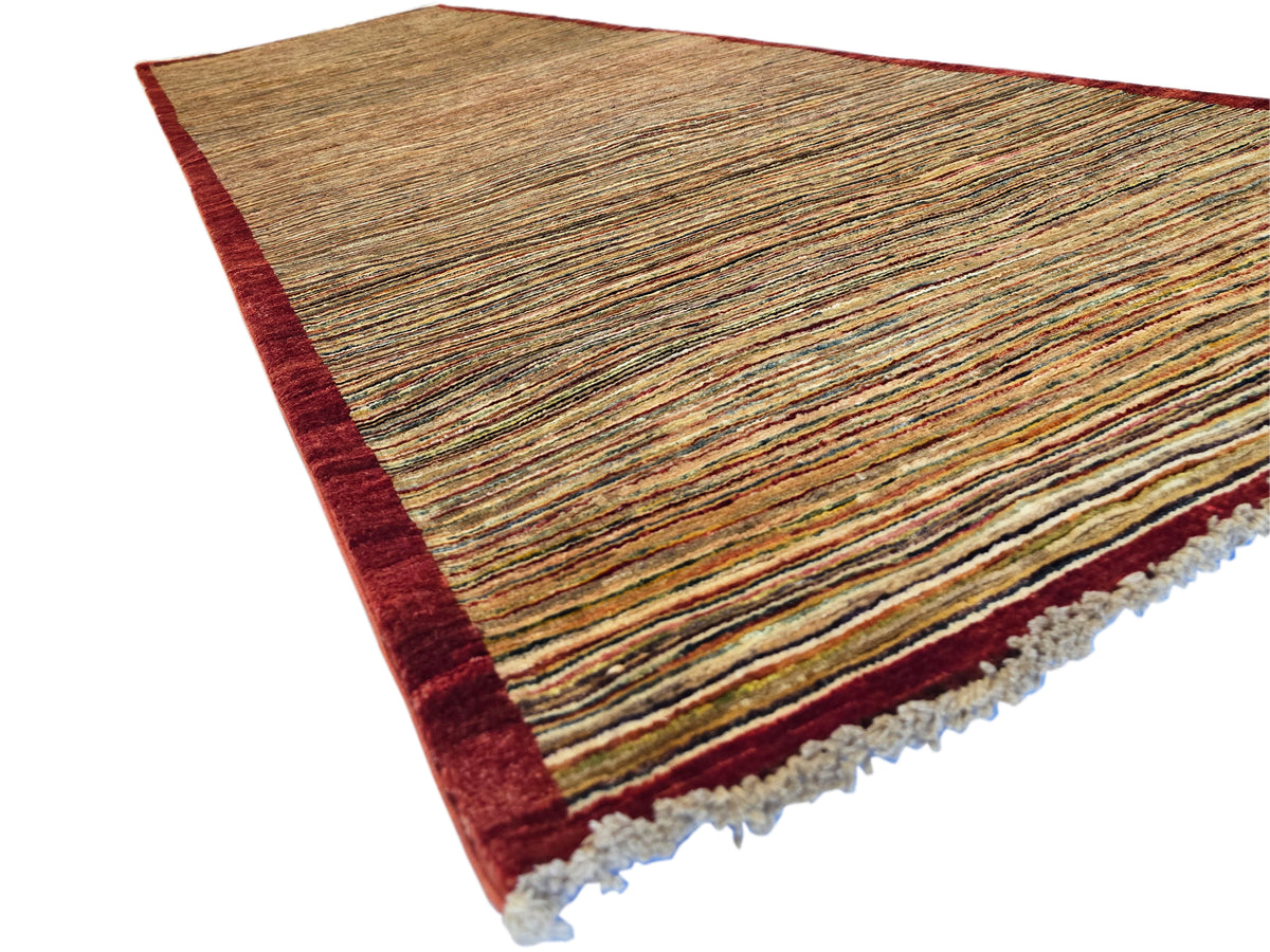 Gabbeh runner rug corner view, brown striped texture with dark red band and light fringe.