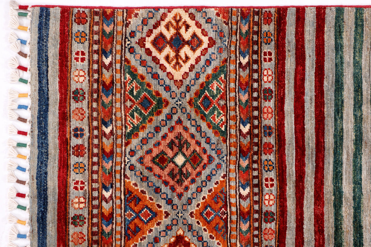 Multicolor flatweave rug detail with central diamond motif, striped bands, and fringe
