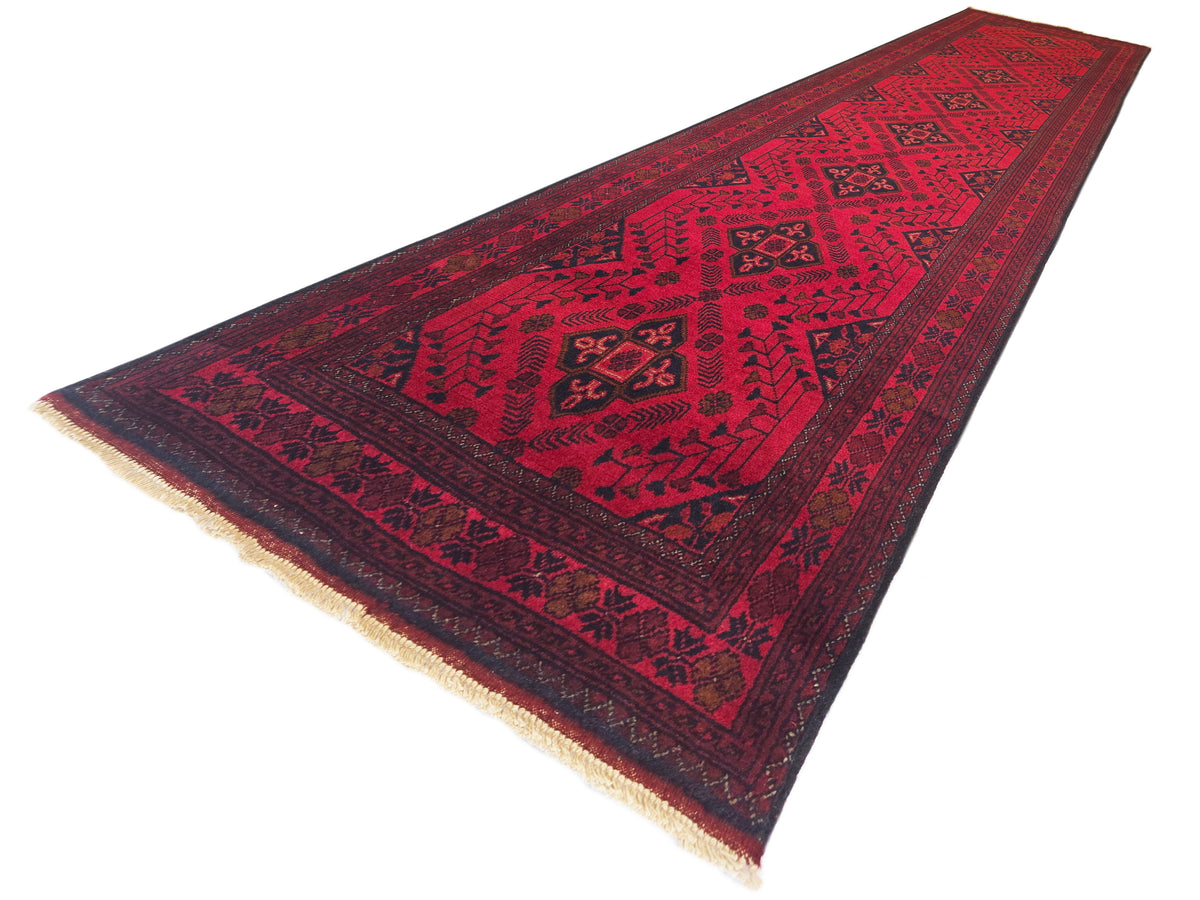 Red rug runner with dark geometric medallion pattern and short fringe trim