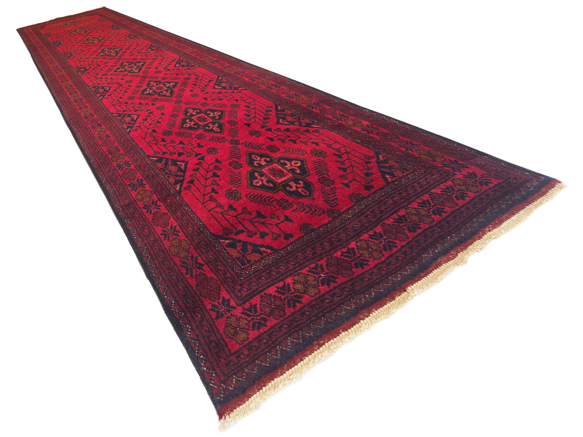 Red rug runner with bold geometric motifs and fringe along the edges